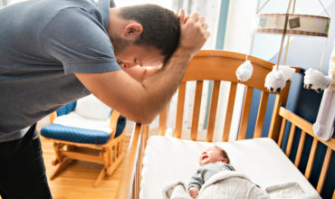 Tired father with Upset Baby Suffering with Post Natal Depression.