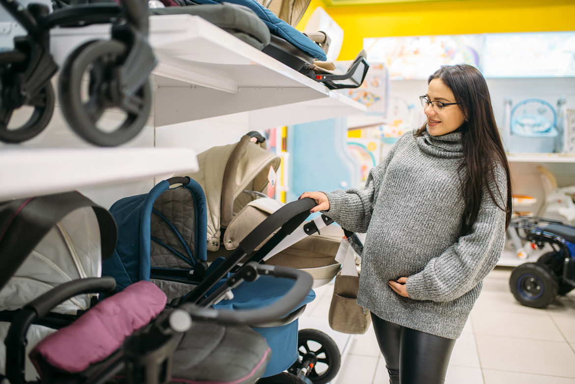 Femme enceinte choisissant une poussette dans un magasin de puériculture