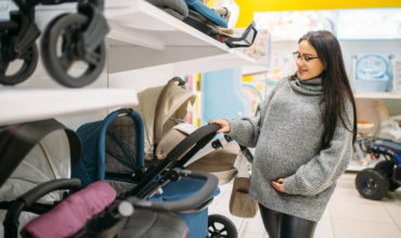 Femme enceinte choisissant une poussette dans un magasin de puériculture