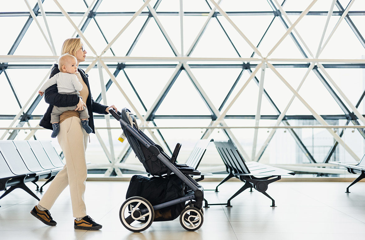 Maman avec bébé et poussette de voyage à l’aéroport