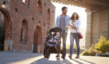eunes parents en voyage avec bébé dans une poussette tout-terrain