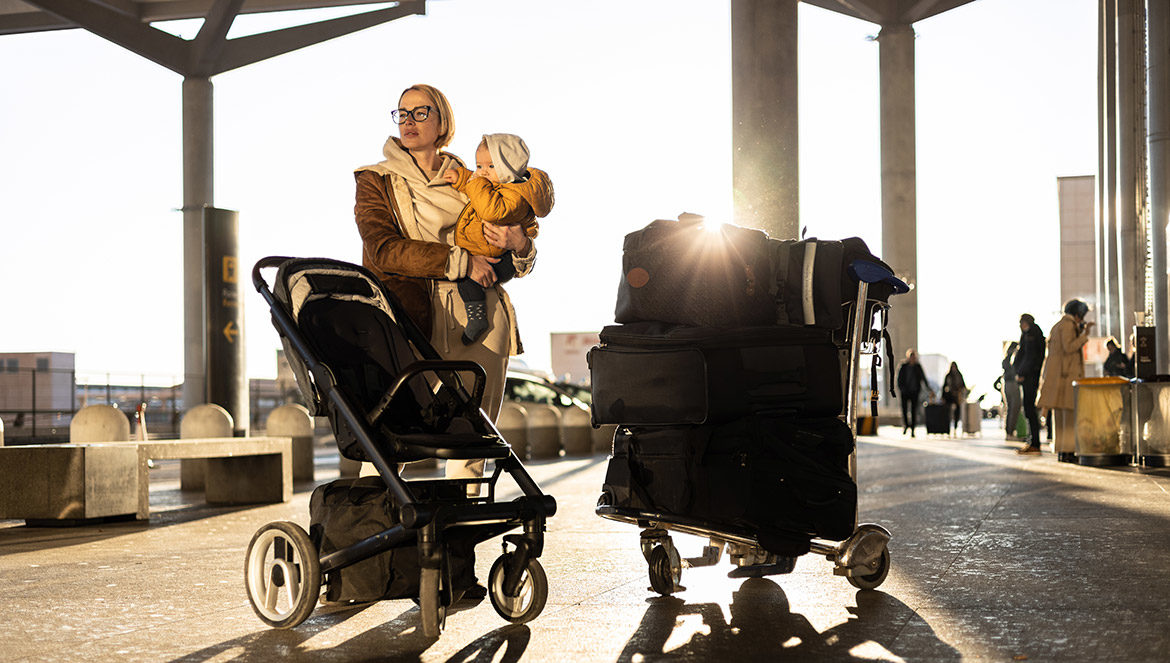 Maman avec bébé, poussette et bagages à l’aéroport avant le voyage