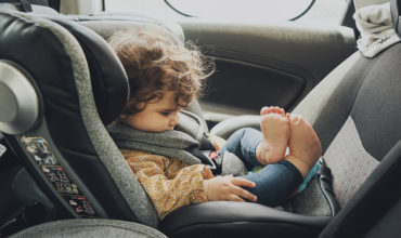 Bébé installé dos à la route dans un siège auto i-Size avec harnais bien ajusté