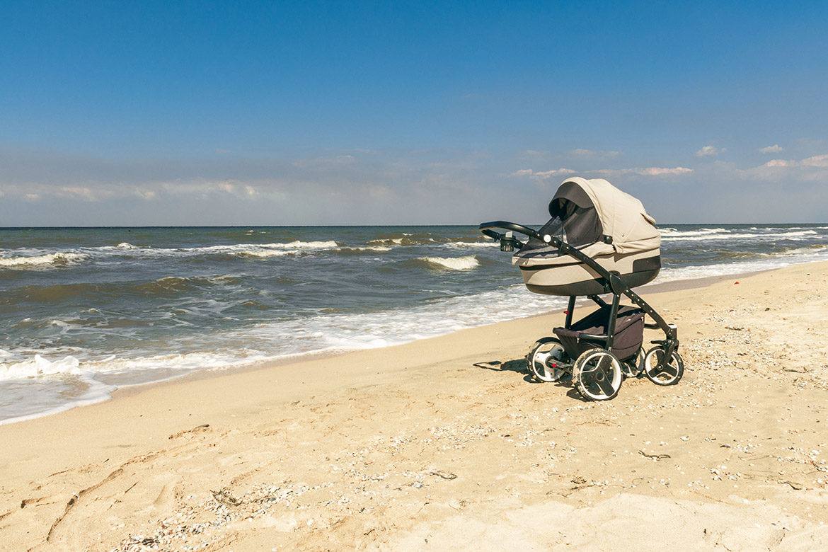 Poussette de bébé avec nacelle sur la plage en bord de mer 