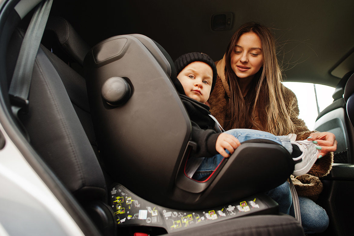 Jeune maman installant son bébé dans un siège auto, dans un taxi.