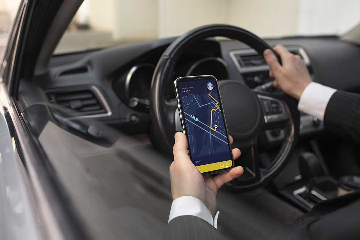 Main d’un chauffeur VTC tenant un smartphone avec une application de navigation.