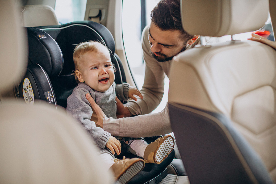 Papa qui prend dans ses bras un bébé qui pleure en voiture dans son siège auto