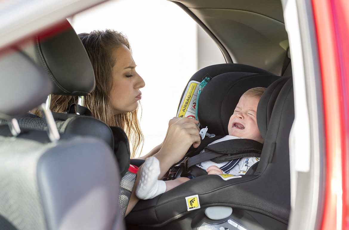 Bébé qui pleure en voiture dans son siège auto avec maman qui lui donne une tétine