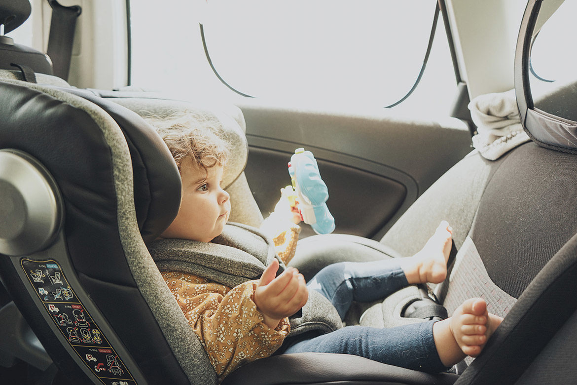 Bébé assis confortablement dans son siège auto avec un jouet, un pare-soleil et un miroir sur le siège